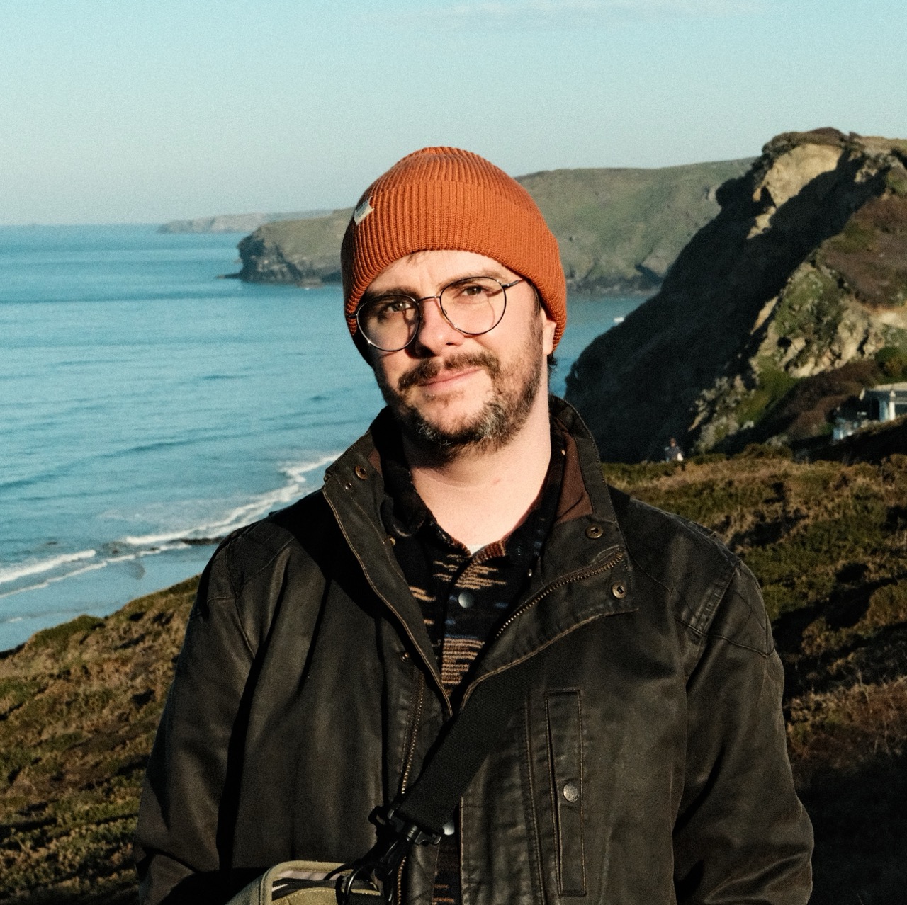 Rob Moran on the Cornish coast, wearing an orange beanie and glasses